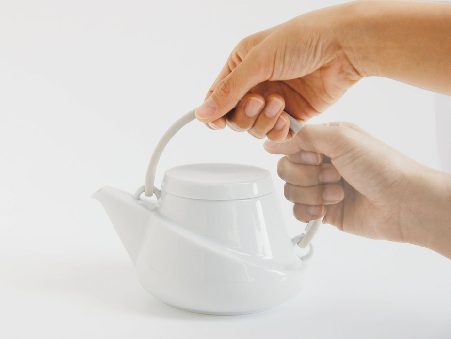 Zwei Hände halten RIDGE weisse Porzellan Teekanne Teegeschirr vor einem weissen Hintergrund - Two hands hold white porcelain teapot against a white background