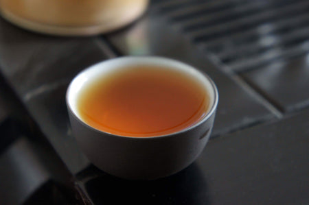 Flüssiger Pu-Erh-Tee in schwarzer Teetasse - Liquid Pu-Erh tea in black teacup
