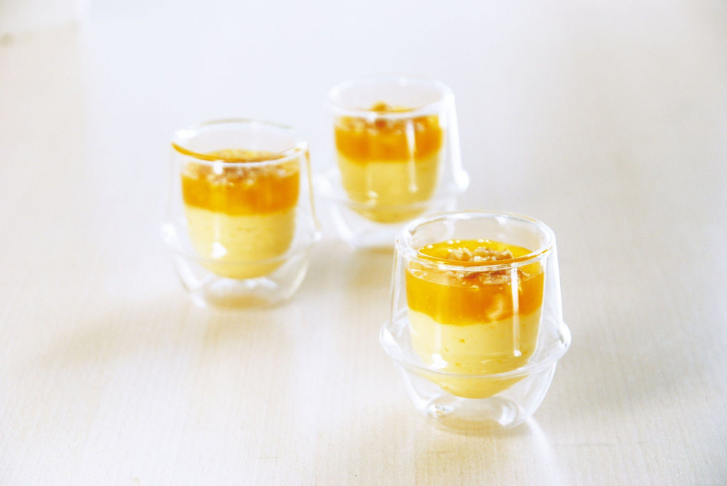 drei kleine transparente Glasteetassen mit Dessert darin - three small transparent glass tea cups with dessert in them