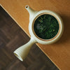 Bio Loser blatt Kukicha in weisser Teetasse auf Holztisch - Organic Kukicha loose leaf Tea in white teapot on wooden table