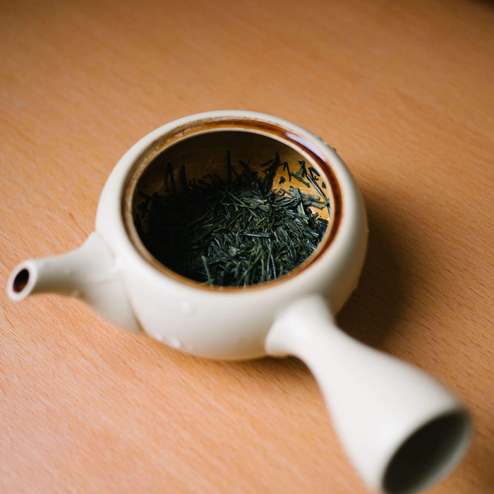 Bio Premium Sencha Loser-blatt Tee im weisse Teekanne auf Holztisch - Organic Premium Sencha Green Tea in white teapot on wood table