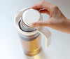 Hand stellt Eistee-Ei in hohe transparente Teekanne  - hand puts iced tea infuser in tall transparent tea jug