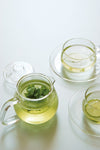 Grosse UNITEA Glas Teekane neben zwei glas Tee Kanne mit Grüner Minztee Tee - Large UNITEA glass teapot next to two glass teacups with green mint tea